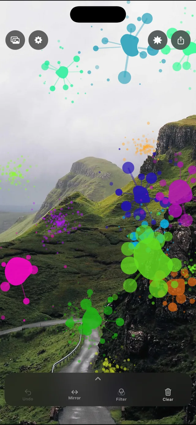 Colorful paint splatters over a photo of a mountain valley